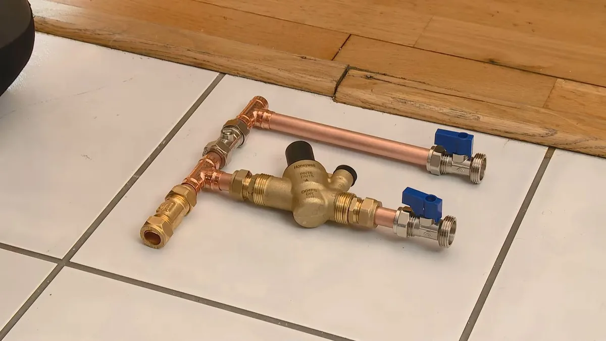 Copper pipe, pex tubing, and brass fittings laid out for comparison for Galvanized vs. Copper vs. PEX Pipe in Older FV Homes in Fountain Valley