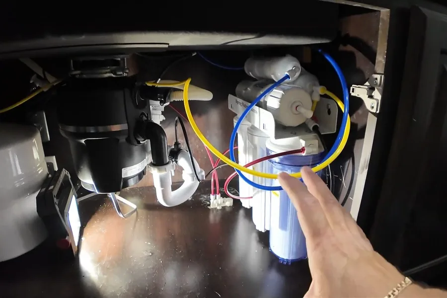 Garbage disposal wiring, drain, and mounting connections under a sink for Garbage Disposal Services in Fountain Valley, CA in Fountain Valley during inspection.