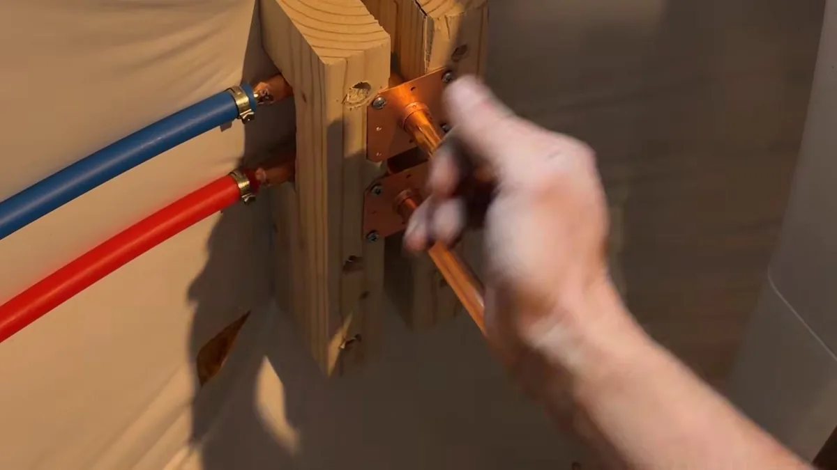 Hand reaching toward a wall shutoff valve for How to Shut Off Your Water in an Emergency in Fountain Valley