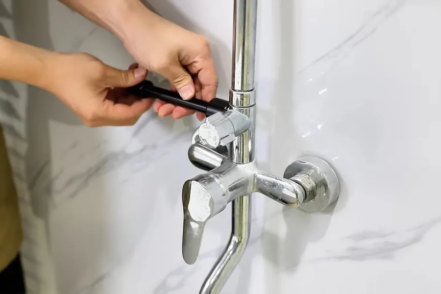 Hand tightening a chrome faucet connection at the wall for Faucet & Fixture Installation in Fountain Valley, CA in Fountain Valley