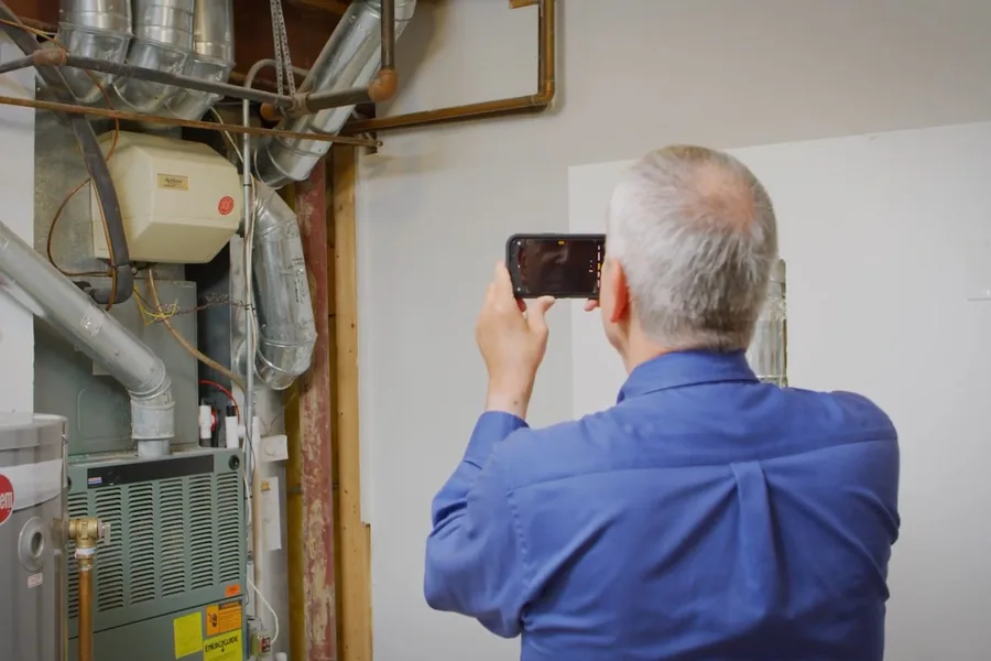 Technician checking water heater components with a phone light for Plumbing in Fountain Valley, CA in Fountain Valley